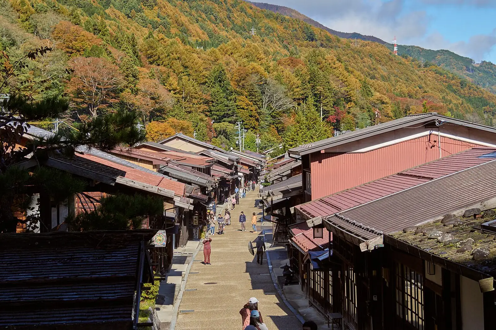 Narai-juku's long main street of wooden houses with autumn trees on the hillside